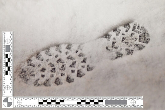 Winter boot footprints in fresh snow on sidewalk as evidence