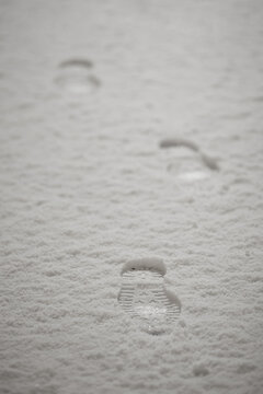Winter boot footprints in fresh snow on sidewalk as evidence