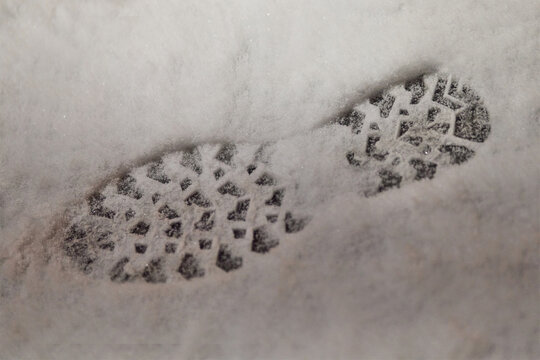 Winter boot footprints in fresh snow on sidewalk as evidence