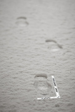 Winter boot footprints in fresh snow on sidewalk as evidence