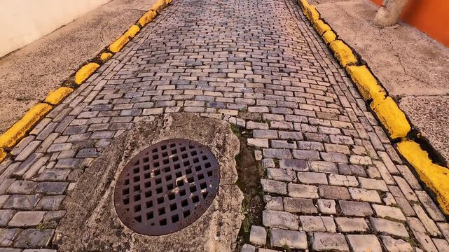 Walking video over a blue tones cobblestone street in old San Juan during the day.