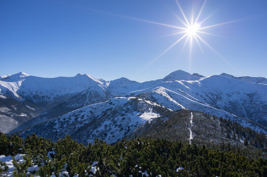 View of Volovec in Western Tatras with snow-covered peaks under a bright sun and clear blue sky in Witow, Lesser Poland, Poland.