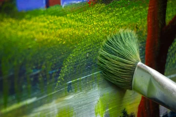 Fotobehang Schilderij Close-up of paintbrush applying smooth oil paint strokes on colorful landscape painting  © Slime Photography