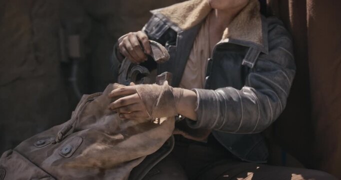 Tired, dirt covered woman taking sci-fi relic out of bag and talking to someone