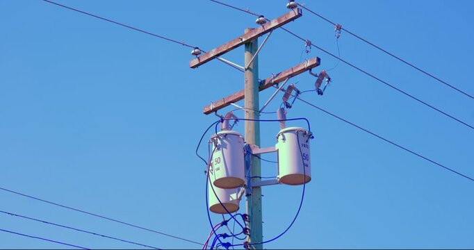 Wooden power line post supporting distribution transformers, power cables, and insulators