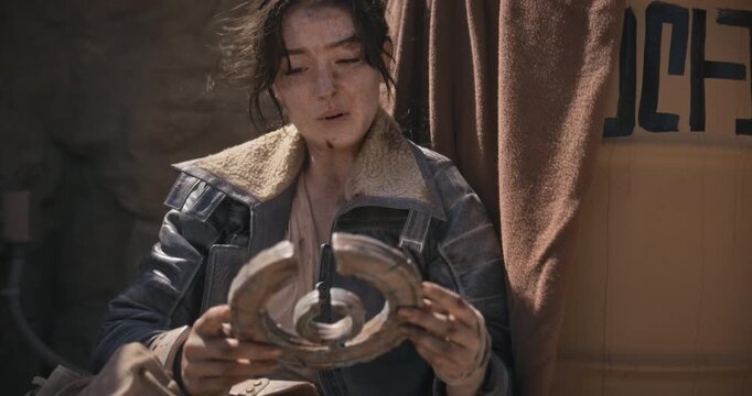 Exhausted, beat up female adventurer staring at strange artifact as she rests - tilt up shot