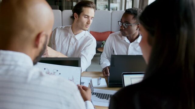 Team discusses company strategy in office while analyzing data and graphs to make informed decisions for future growth and development