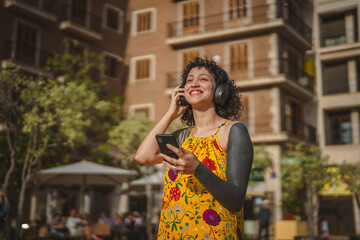 Fototapeta premium Young woman enjoying music on smart phone in city street