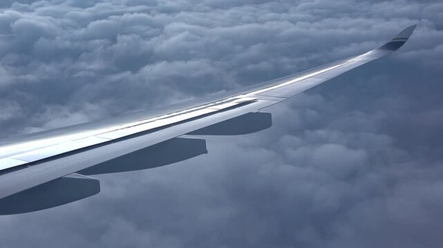 Cabin view: an airplane extending spoilers, descending slowly above the clouds.