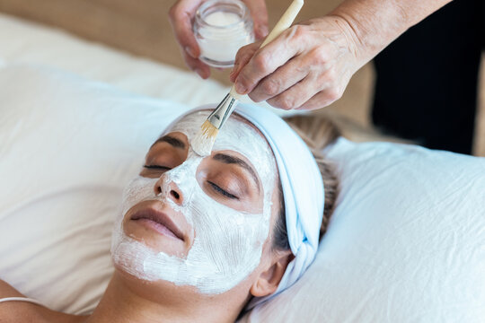 Beautiful young woman with clay facial mask in beauty spa. Detox ritual.