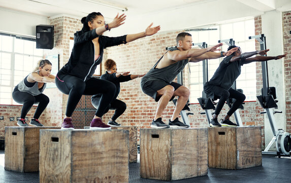 Team, squat or people in fitness class with crate, cardio or calorie burn in balance training. Exercise, athletes or instructor with equipment, group session or intense workout in weight loss.