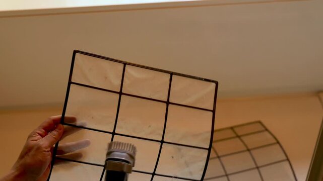 エアコンのフィルターを掃除機で清掃するシーン