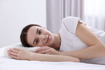 Obraz premium Woman lying on bed with orthopedic pillow at home