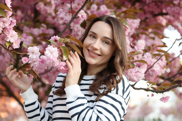 Fototapeta premium Beautiful woman near blossoming tree on spring day