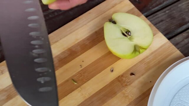 Fresh organic apple divided into slices on wooden surface with detailed fruit texture and simple homemade kitchen preparation atmosphere.