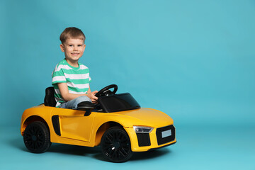 Fototapeta premium Little child driving toy car on light blue background, space for text