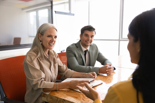 Diverse business professionals engaged in meeting discussion in corporate office. Female applicant answers questions during hiring job interview with hr managers. Staffing, employment, human resources