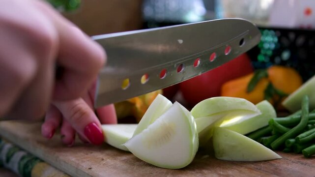 cutting board surrounded by cucumbers, green beans, pink tomatoes, flowers, and young zucchini. Warm sunlight highlights a cozy homemade vegan cooking process with natural seasonal vegetables .