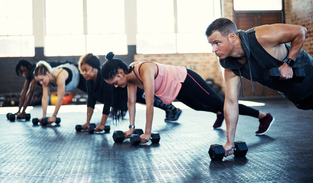 Fitness, strength training or people in gym class with dumbbells, power or endurance in bodybuilding. Exercise, renegade row or athletes with equipment, group session or workout for muscle gain.