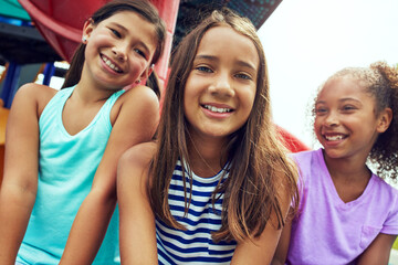 Fototapeta premium Playground, kids and girls with smile for break, summer holiday and hang out together for bonding. Group fun, portrait and childhood friends relax on weekend by jungle gym, diversity and low angle