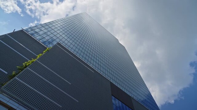 Low angle steady camera motion around modern office skyscraper with reflective glass facades, symbolizing business growth, corporate success and future urban development