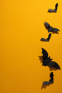 Halloween paper bat vertical decoration on bright orange background with dramatic shadow