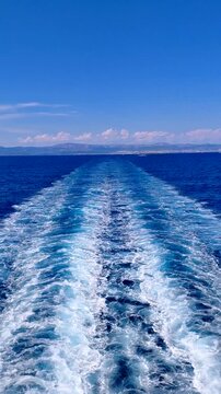 Stunning wide foam wake trail behind a fast ferry on the deep blue Adriatic Sea in Croatia. Scenic maritime journey between Split and Vis under a clear summer sky with distant mountains