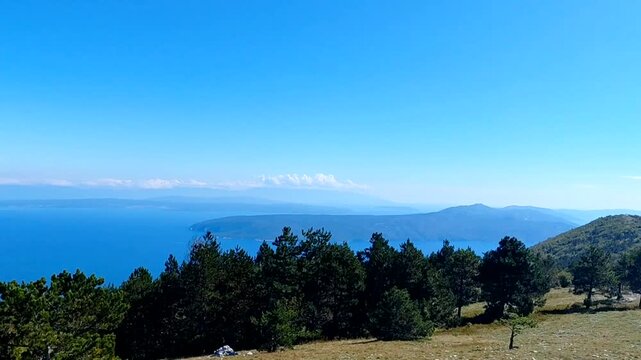 Stunning panoramic view from the Učka mountain ridge in Croatia's Nature Park. The vast blue Adriatic Sea, Kvarner Bay, and distant islands meet the clear sky on a beautiful, sunny day