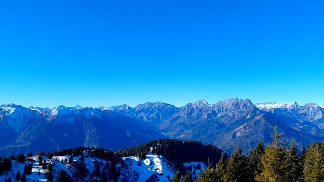 Stunning aerial view of the Carnic Alps surrounding Tolmezzo, Italy. The majestic Monte Amariana peak towers over the Tagliamento valley in a scenic winter panorama of the Friuli-Venezia Giulia region