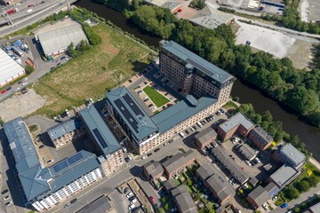 Obraz premium Aerial drone photograph of a residential apartment complex beside the canal in Leeds West Yorkshire UK showing modern urban housing rooftop solar panels and regenerated waterfront development