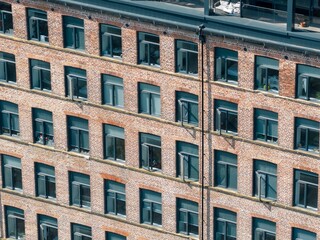 Obraz premium Close up aerial drone photograph of a modern brick apartment building facade in Leeds West Yorkshire UK showing geometric window patterns and urban residential architecture on the converted factory
