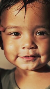 Vertical video: Curiosity driving toddler in green shirt touching right eyelid, blinking at home