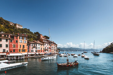 Fototapeta premium Boats moored in Portofino harbor in front of colorful waterfront houses under a deep blue sky on the Ligurian coast, Italy