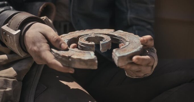 Beat up girl staring down at sci-fi object and talking to someone off screen - closeup shot