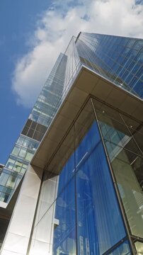 Wide angle dolly camera movement looking up modern office tower business building with blue sky reflections, skyscraper in financial district, architecture and success concept