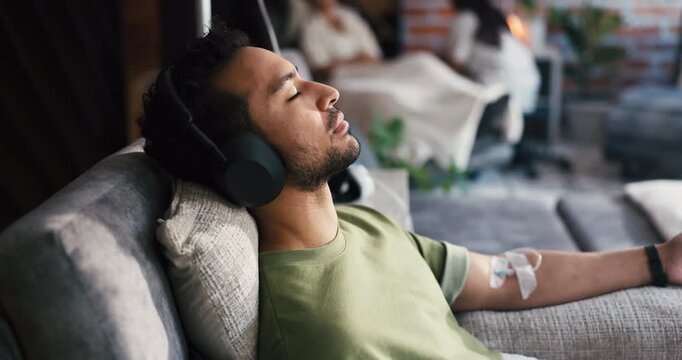 Man, headphones and drip therapy in lounge, relax or listen to music with saline solution for immune system boost. Person, audio streaming and iv for wellness benefits, vitamin or mineral infusion