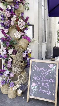 EDITORIAL: LONDON, UNITED KINGDOM - MAY 26, 2026, 7:15 PM: A beautiful vertical 4K static close-up shot of a  flower  arch decoration next to an inspirational text sign Bayley and Sage shop, Ebury Str