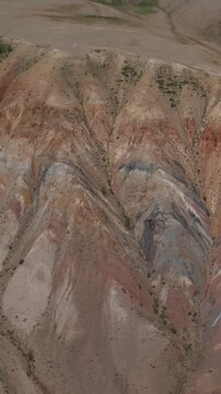 Drone footage of layered red, gray and beige clay slopes and eroded ridges in Kyzyl-Chin valley, Altai Mountains, Russia, arid wilderness landscape