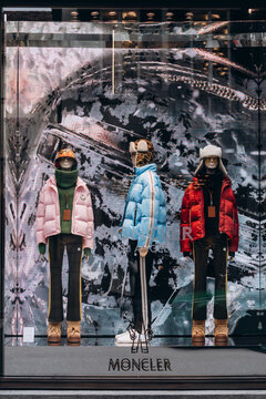 Milan, Italy - 4.12.2021: Moncler storefront window display with mannequins dressed in colorful puffer jackets and winter clothing, presenting urban fashion styles and luxury outerwear trends