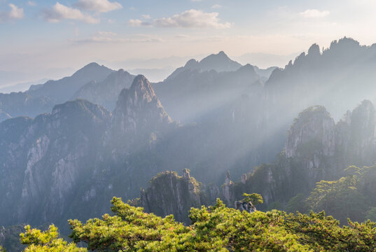 View of the majestic granite peaks and pine trees of Huangshan under sunbeams and misty sky in Huangshan City, Anhui, China.
