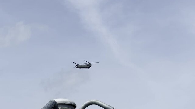 Heavy lift chopper passing over silos panning