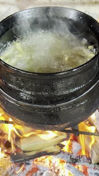 cocinando papas fritas en grasa, en olla de fundici&oacute;n a las brasas