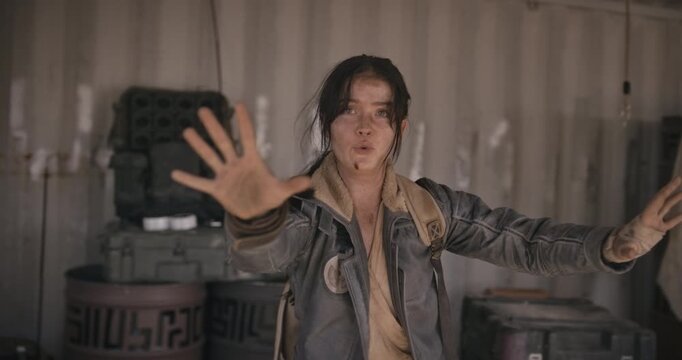 Dirty woman holding up hands to defuse situation then picks up ball and aims it like a weapon