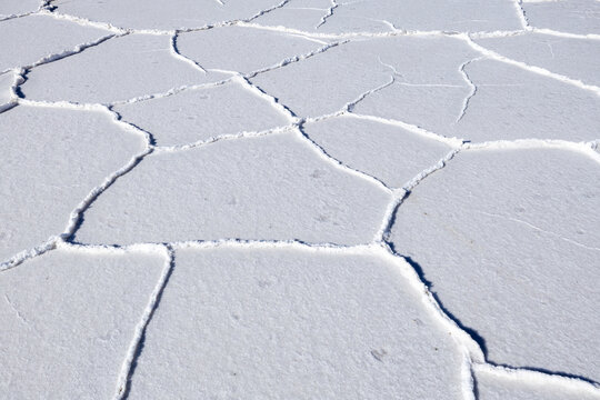 View of Uyuni Salt Flat showing hexagonal salt crust patterns and cracked white surface under bright sunlight in Potosi Department, Bolivia.