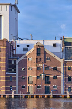 Wormer, Netherlands - 06 May 2026: View of the historic Donau building at the Ebro Foods Lassie rice factory along the Zaan river during sunset.
