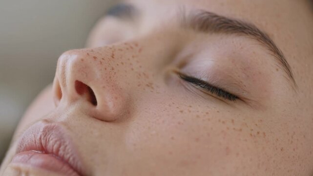 Close up of freckled woman's face with eyes closed in serenity