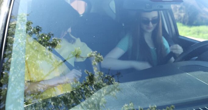 Woman fastening safety belts in car, view through windshield
