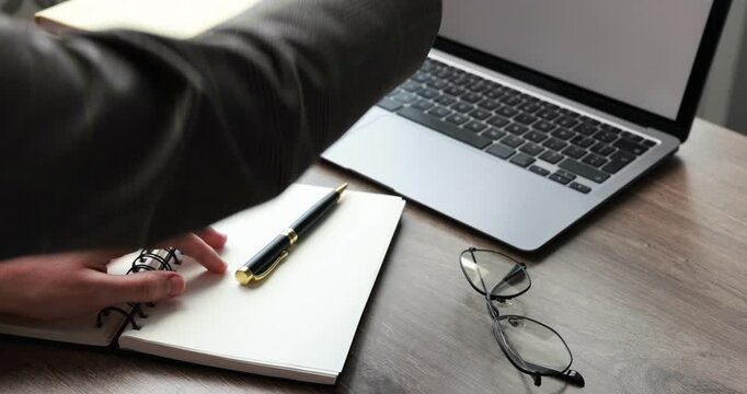 Businesswoman putting stylish glasses onto wooden table and closing laptop in office, closeup
