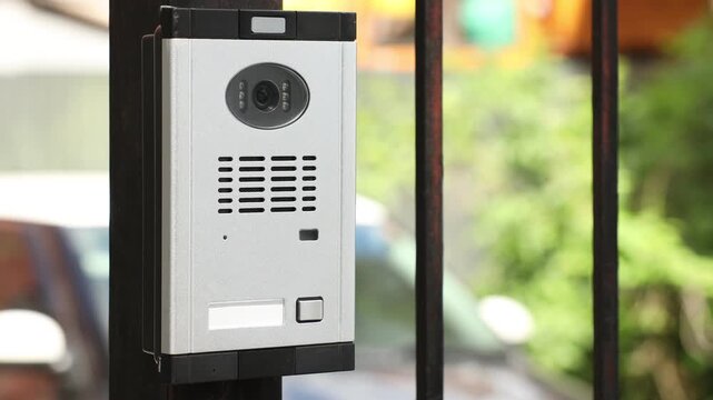 Modern intercom system on gate outdoors, closeup. Camera moving right