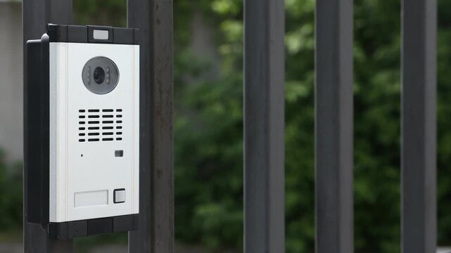 Modern intercom system on gate outdoors, closeup. Camera moving right